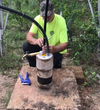 Water pump filling a black trough in a forest clearing