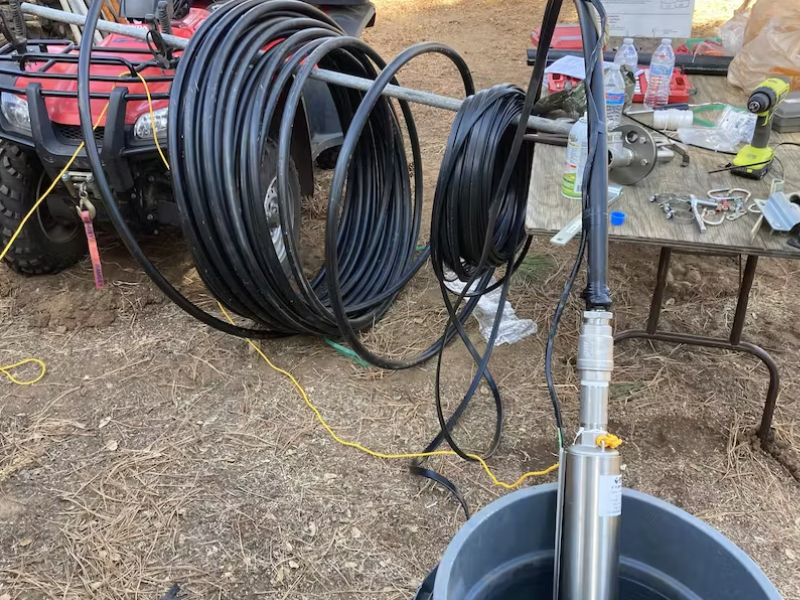 DIY installation setup from RPS Water Pumps with coiled tubing on a red ATV and equipment on a table outdoors.
